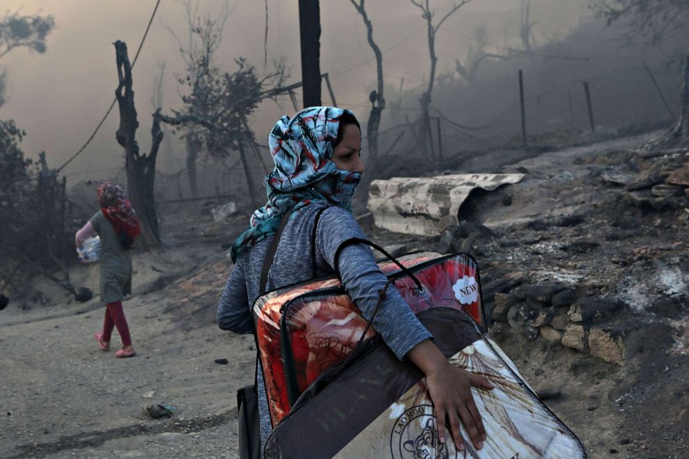 PHOTO: A migrant carries her belongings following a fire at the Moria camp for refugees and migrants on the island of Lesbos, Greece, Sept. 9, 2020.