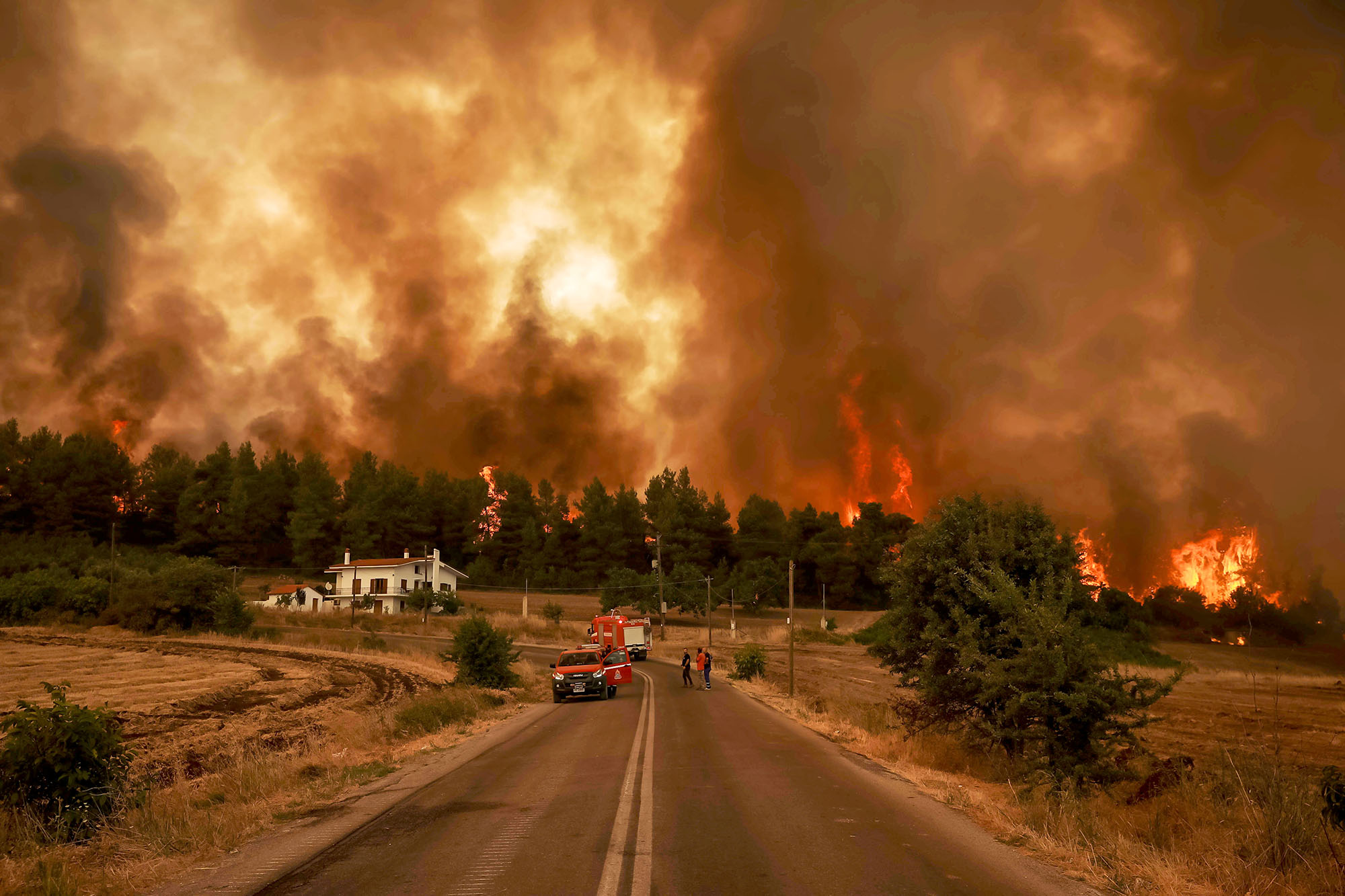 PHOTO: Flames rise near a house as a wildfire burns in the village of Kirinthos, on the island of Evia, Greece, Aug. 6, 2021.