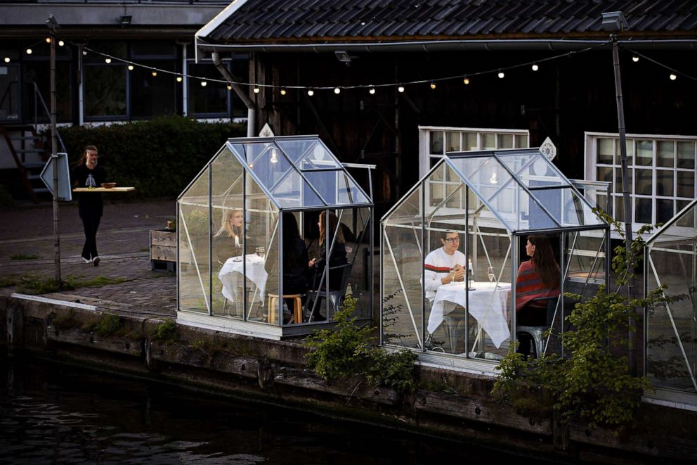PHOTO: People have dinner on a test evening for so-called quarantine greenhouses, in Amsterdam, on May 5, 2020, as the country fights against the spread of the COVID-19.