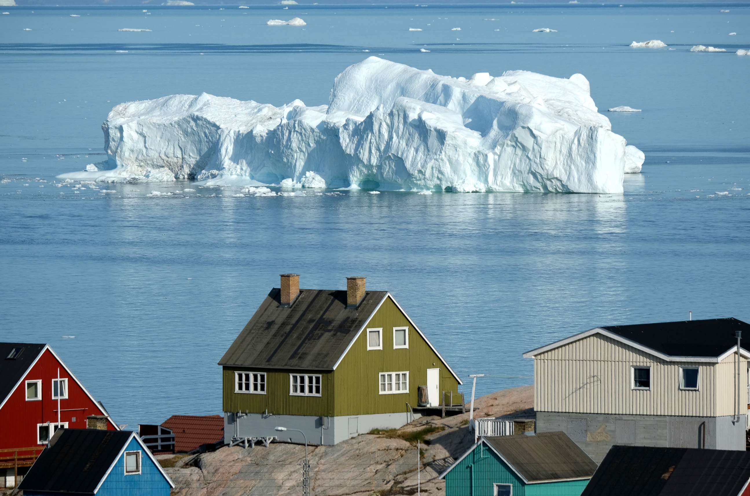 PHOTO: An iceberg floats in Disko Bay behind houses during unseasonably warm weather, July 30, 2019, in Ilulissat, Greenland.