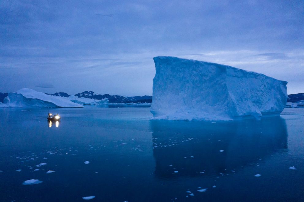 PHOTO: A boat navigates at night next to large icebergs in eastern Greenland, Aug. 15, 2019.