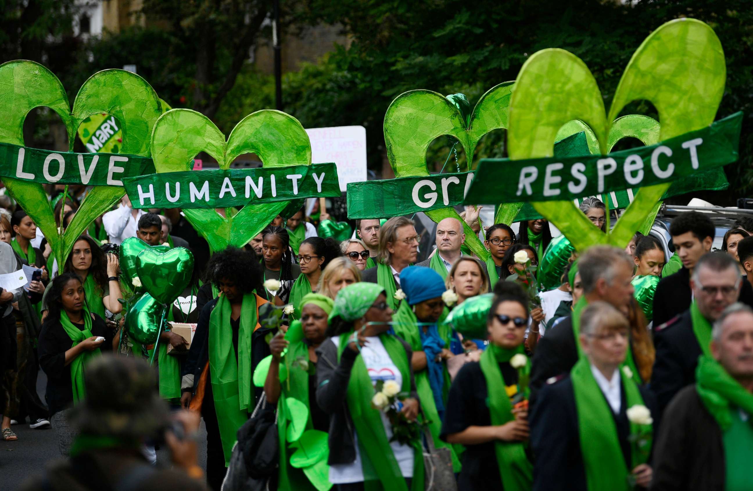 PHOTO: Friends and relatives of victims of the Grenfell fire wear symbolic green, as they take part in a silent procession to mark the one year anniversary of the fire in London, June 14, 2018.