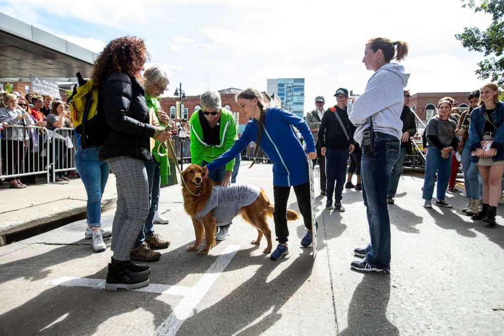 PHOTO: Climate activist Greta Thunberg pets Cleo the "Climate Dog," a golden-retriever, before speaking to reporters after the "Town-Gown Climate Accord" hosted by the Iowa City Climate Strikers, Oct., 4, 2019, in Iowa City, Iowa.