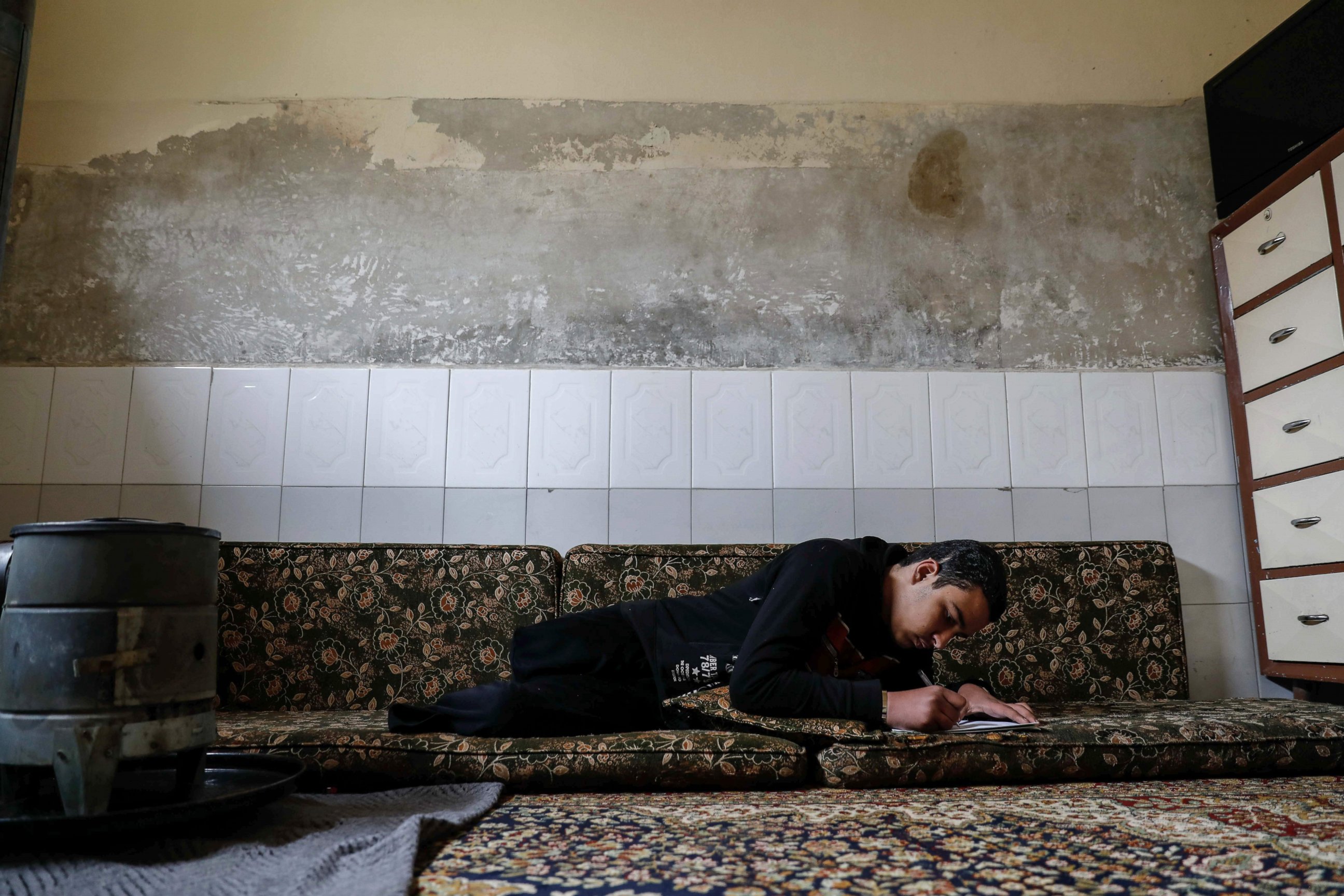 PHOTO: Mute 17-year-old Syrian Adnan, who lost both legs in 2014 following an airstrike as he was walking towards his father's store from school, does his homework at his home, in Douma, on the outskirts of the capital Damascus, Feb. 16, 2017. 
