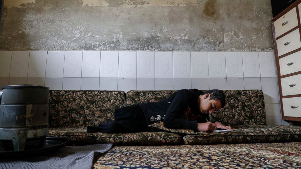PHOTO: Mute 17-year-old Syrian Adnan, who lost both legs in 2014 following an airstrike as he was walking towards his father's store from school, does his homework at his home, in Douma, on the outskirts of the capital Damascus, Feb. 16, 2017. 

