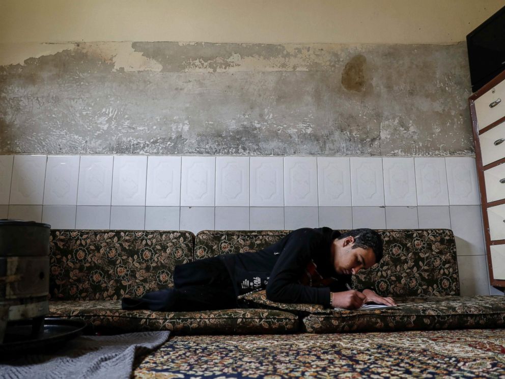 PHOTO: Mute 17-year-old Syrian Adnan, who lost both legs in 2014 following an airstrike as he was walking towards his fathers store from school, does his homework at his home, in Douma, on the outskirts of the capital Damascus, Feb. 16, 2017.