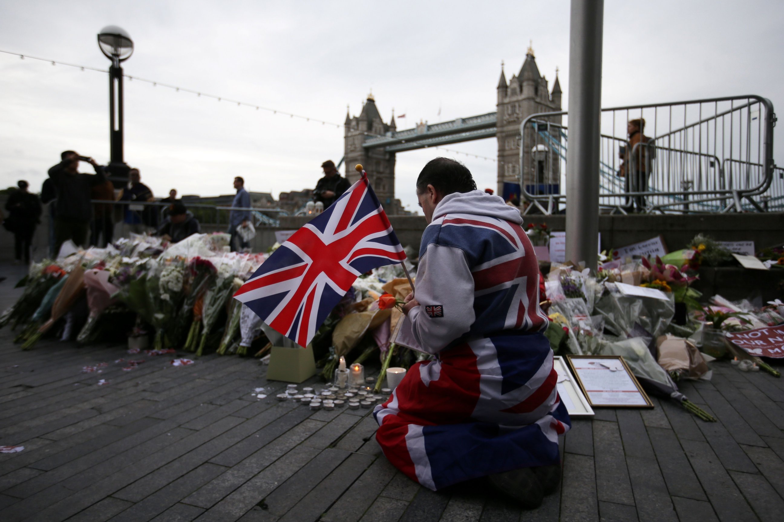 PHOTO: A man holds a Union flag as he kneels near flowers laid at Potters Fields Park in London, June 5, 2017, during a vigil to commemorate the victims of the terror attack on London Bridge.