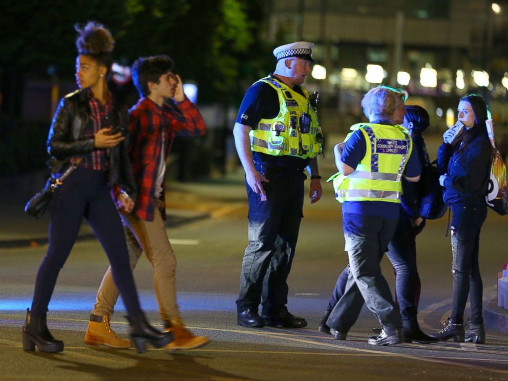 PHOTO: People walk past police near the Manchester Arena on May 23, 2017 in Manchester, England.