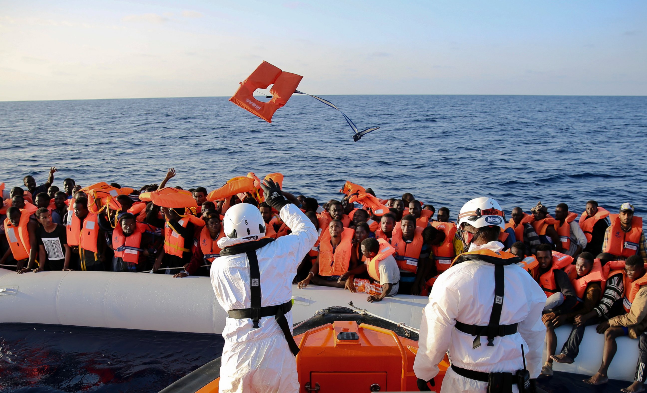 PHOTO: Safety jackets are thrown to migrants on a rubber dinghy from the vessel Responder, run by the Malta-based NGO Migrant Offshore Aid Station (MOAS) and the Italian Red Cross.