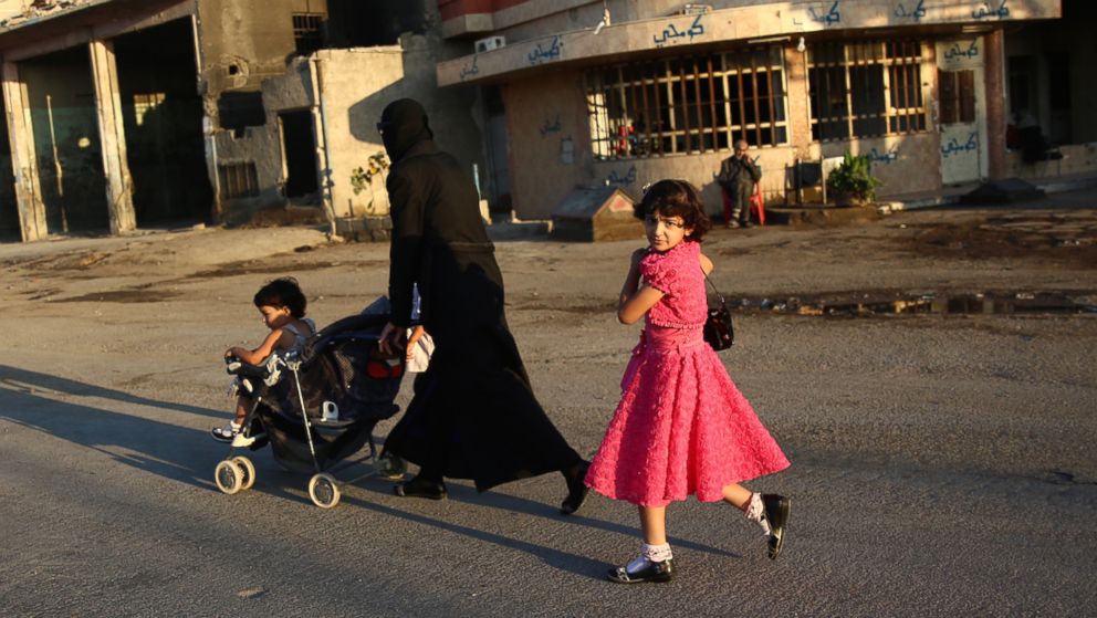 A Syrian girl walks with her mother in the rebel-held town of Douma east of the capital Damascus, July 6, 2016.