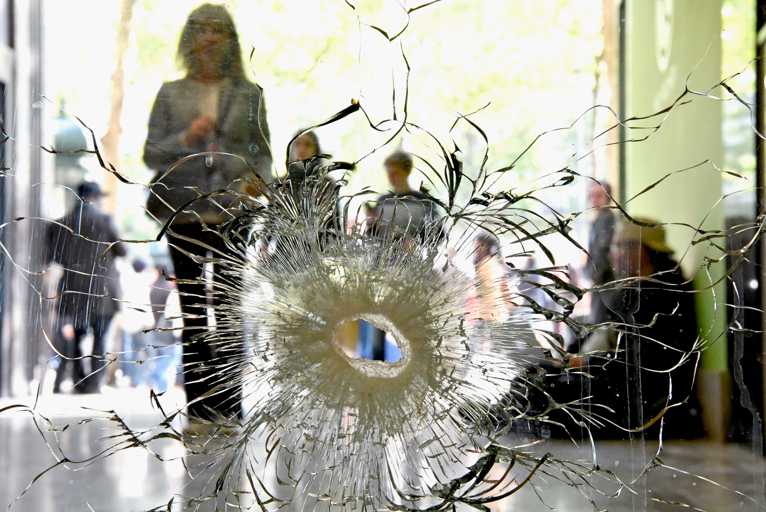 PHOTO: People look at a bullet hole in a window near to the Marks and Spencer on the Champs Elysees in Paris following the shooting of a police officer on April 21, 2017.