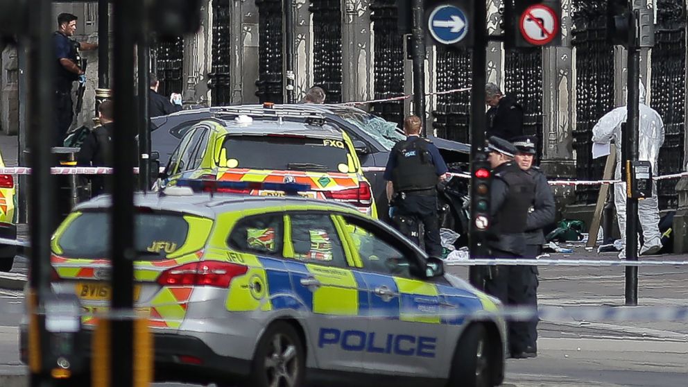 PHOTO: Armed police officers stand guard a grey vehicle that crashed into the railings of the Houses of Parliament in central London on March 22, 2017.