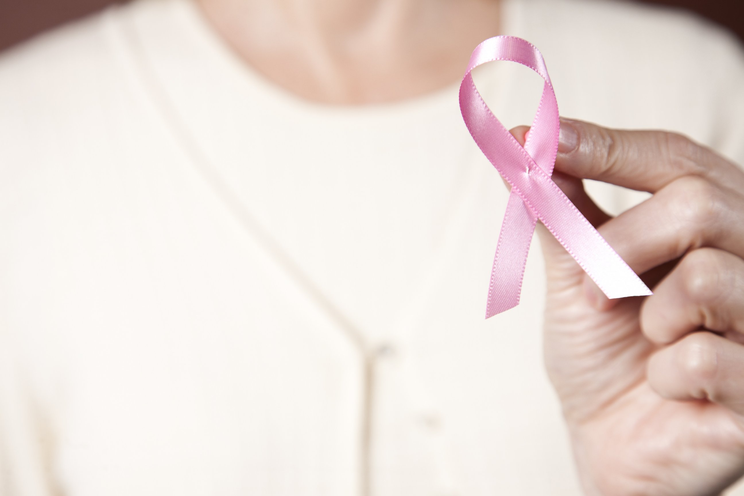 PHOTO: A woman holding a pink Breast Cancer Awareness ribbon. 