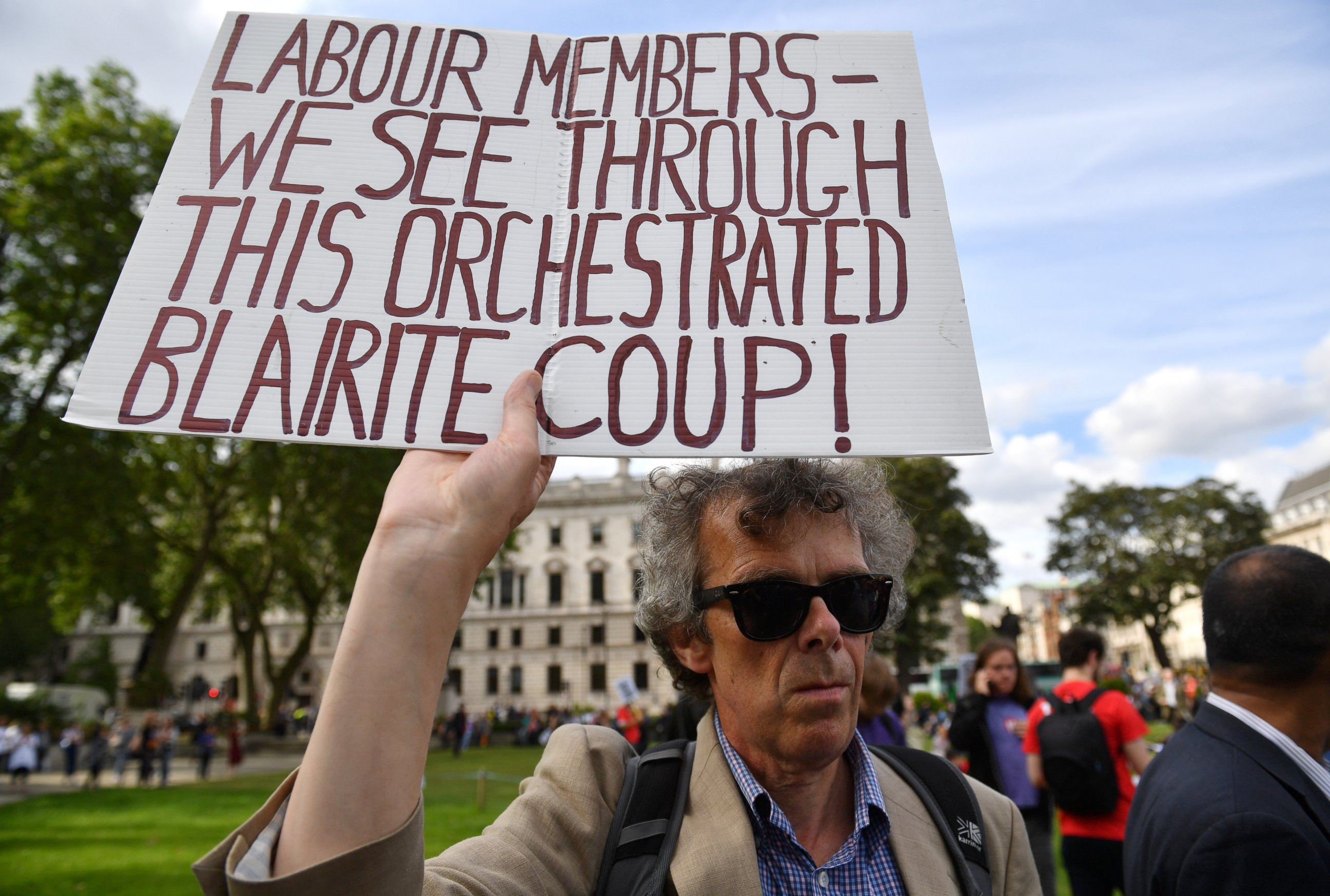 PHOTO: A protester holds up a sign accusing Labour members of a "Blairite Coup" during Momentum's 'Keep Corbyn' rally outside the Houses of Parliament, June 27, 2016 in London.