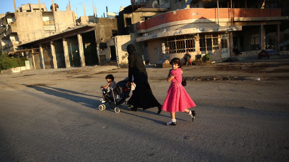 PHOTO: A Syrian girl walks with her mother in the rebel-held town of Douma east of the capital Damascus on the first day of the Eid al-Fitr holiday which marks the end of the Muslim holy fasting month of Ramadan on July 6, 2016.  