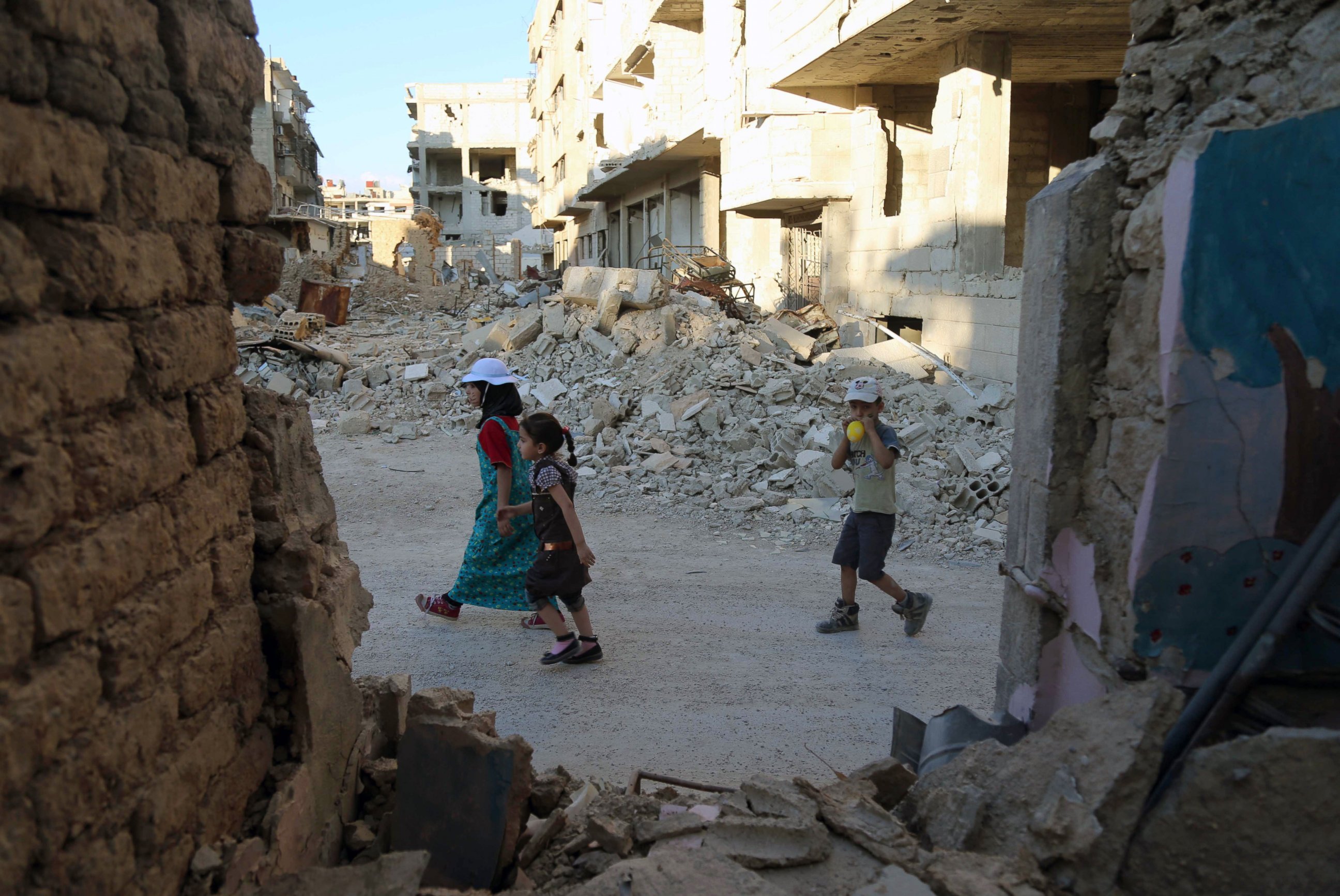 PHOTO: Syrian children walk amidst destruction in Jobar, a rebel-held district on the eastern outskirts of the capital Damascus, ahead of Eid al-Fitr in the war-torn country on July 5, 2016. 