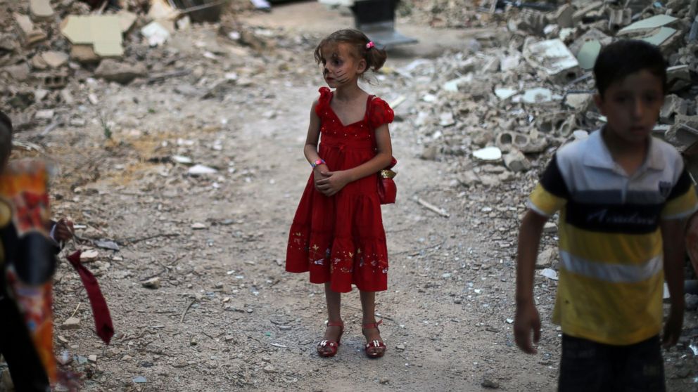 PHOTO: Syrian children stand amidst heavily damaged buildings on the eastern outskirts of the capital Damascus, ahead of Eid al-Fitr holiday in the war-torn country on July 5, 2016. 