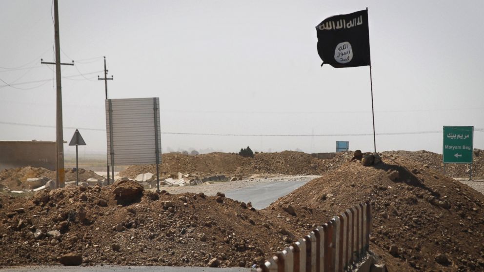 A flag of the Islamic State (IS) is seen on the other side of a bridge at the frontline of fighting between Kurdish Peshmerga fighters and Islamist militants in Rashad, on the road between Kirkuk and Tikrit, on Sept. 11, 2014.