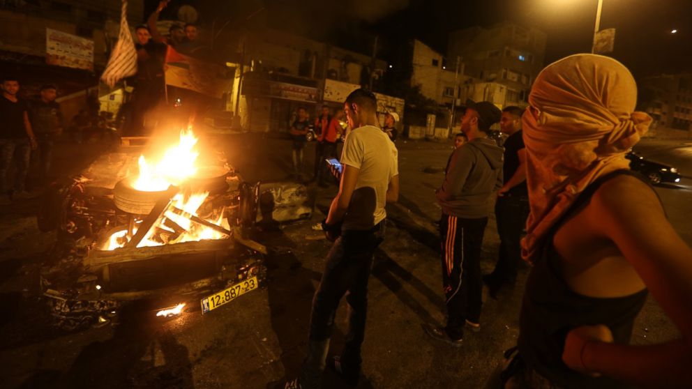 PHOTO: Palestinian youth stand next to a burning car belonging to an Israeli settler, that was set on fire by Palestinians as it entered the northern Palestinian West Bank city of Nablus, early on October 18, 2015.