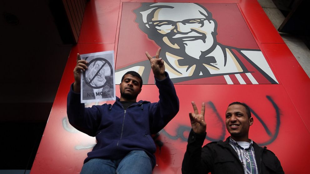 PHOTO: Protestors gesture as they stand next to a Kentucky Fried Chicken restaurant on January 31, 2011 in Cairo, Egypt.  