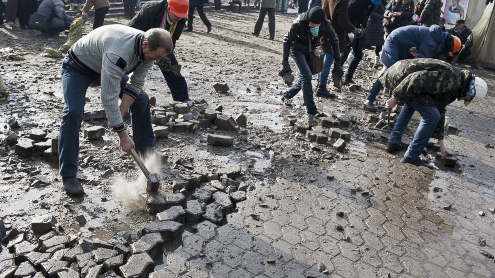 Anti-government protesters dig up cobblestones to use them as rocks against riot police on Kiev's Independence square, Feb. 19, 2014. 