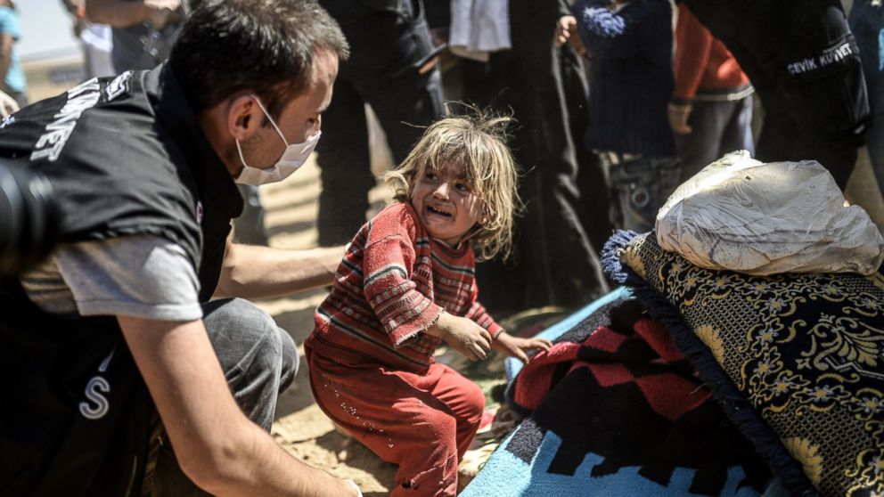 A Syrian Kurdish child cries as Turkish police search families' bags after they crossed the border between Syria and Turkey, Sept. 23, 2014. 
