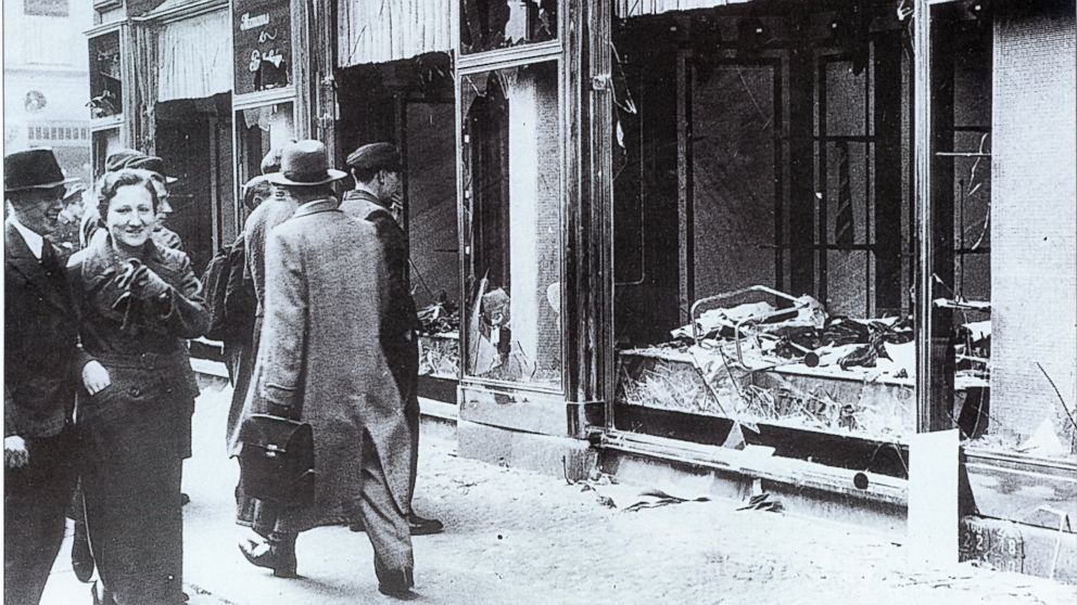 Pedestrians glance at the broken windows of a Jewish owned shop in Berlin after the attacks of Kristallnacht, November 1938. 