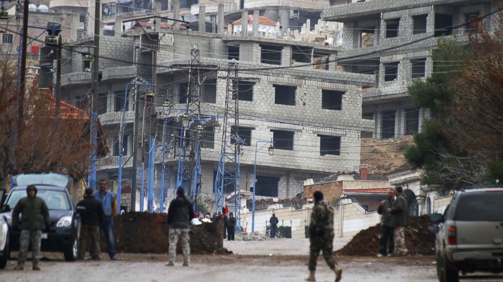 Syrian pro-government forces stand at the entrance of the besieged Syrian town of Madaya as they wait for a convoy of aid from the Syrian Arab Red Crescent on Jan. 14, 2016.