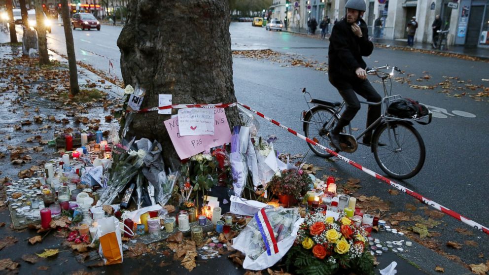 PHOTO: A cyclist pauses to look at candles and floral tributes to victims of the attacks at the Bataclan Theater in Paris on Nov. 17, 2015, where at least 82 people were killed.