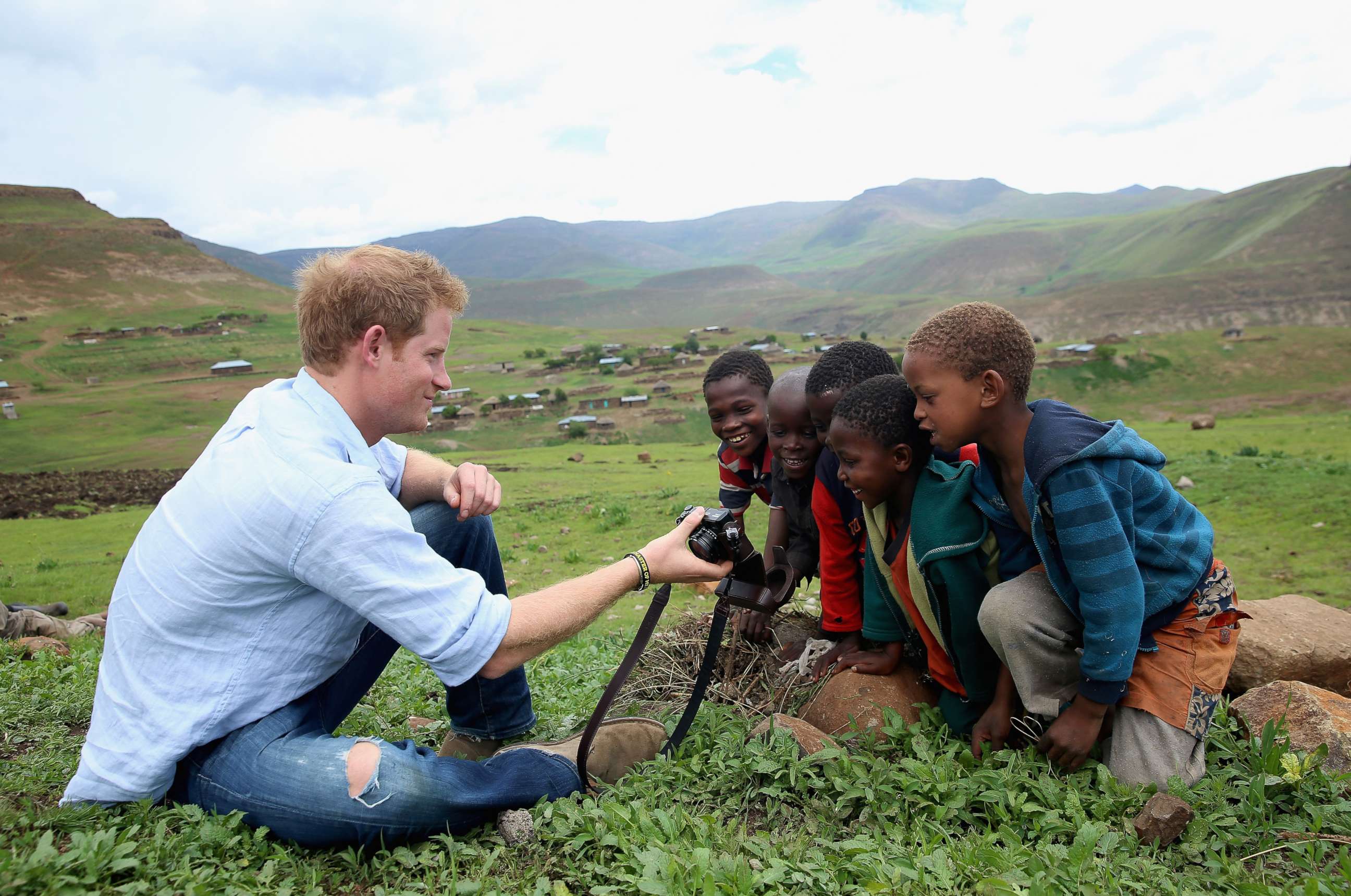 PHOTO: Prince Harry shows children a photograph he has taken on a digital camera during a visit to a herd boy night school constructed by Sentebale on Dec. 8, 2014 in Mokhotlong, Lesotho.