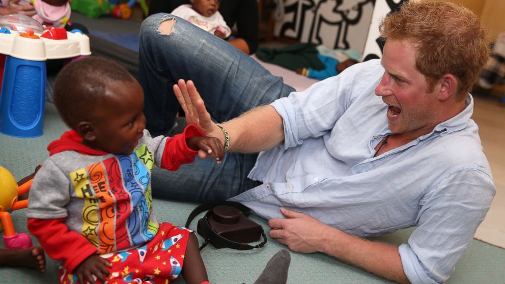 PHOTO: Prince Harry plays with two young children during a visit to the organisation supported by Sentebale, "Touching Tiny Lives," on Dec. 8, 2014 in Mokhotlong, Lesotho.