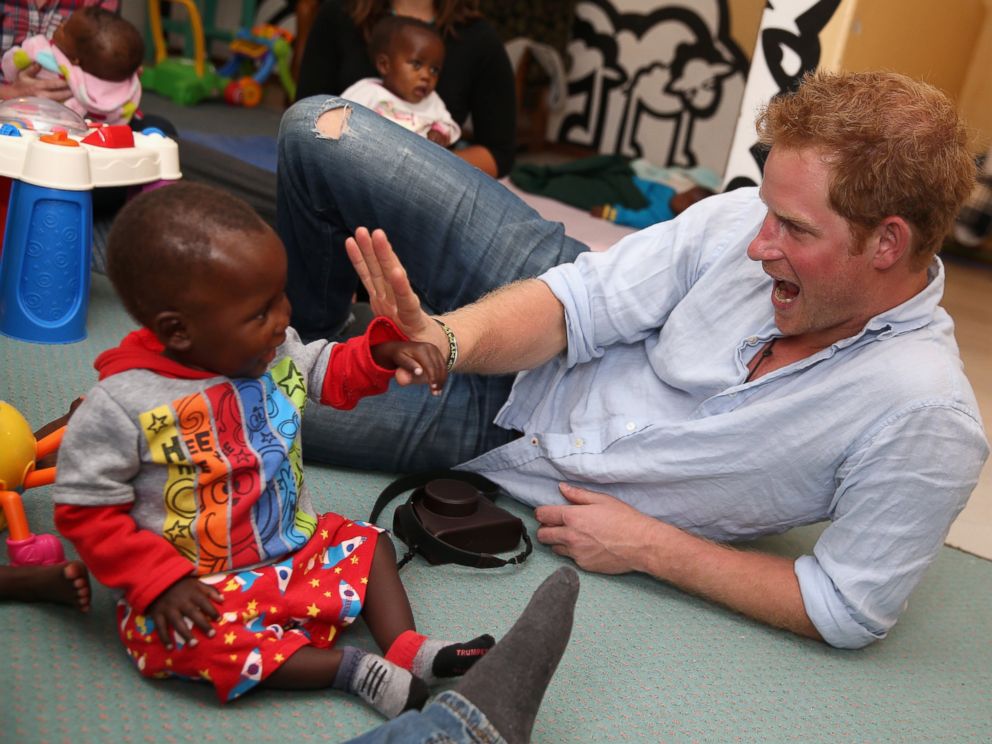 PHOTO: Prince Harry plays with two young children during a visit to the organisation supported by Sentebale, "Touching Tiny Lives," on Dec. 8, 2014 in Mokhotlong, Lesotho.