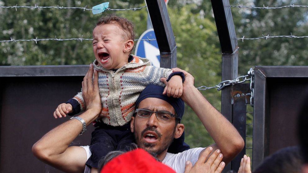 PHOTO: A refugee holds his baby on his shoulders as refugees continue waiting on the Hungarian border in Horgos, Serbia after authorities closed the border on Sept. 16, 2015.