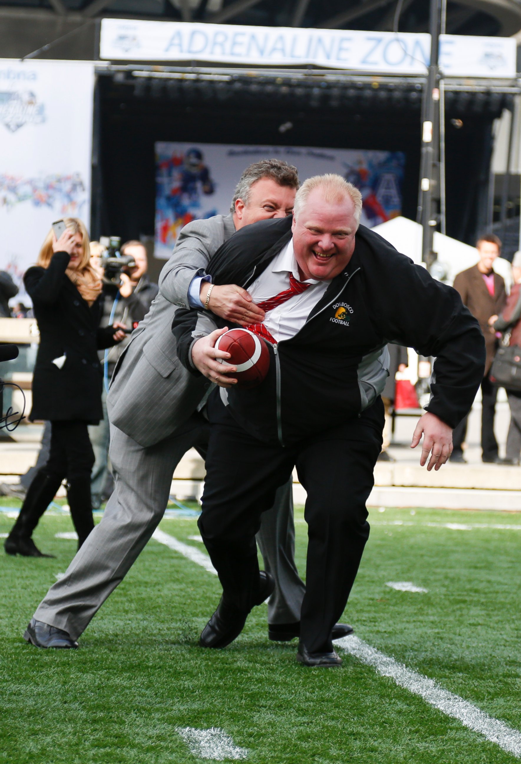 PHOTO: Mayor Rob Ford gets tackled by his Press-Secretary George Christopoulos during Grey Cup celebrations at the CFL Adrenaline Zone at Nathan Phillips Square, Nov. 20, 2012 in Toronto, Canada. 