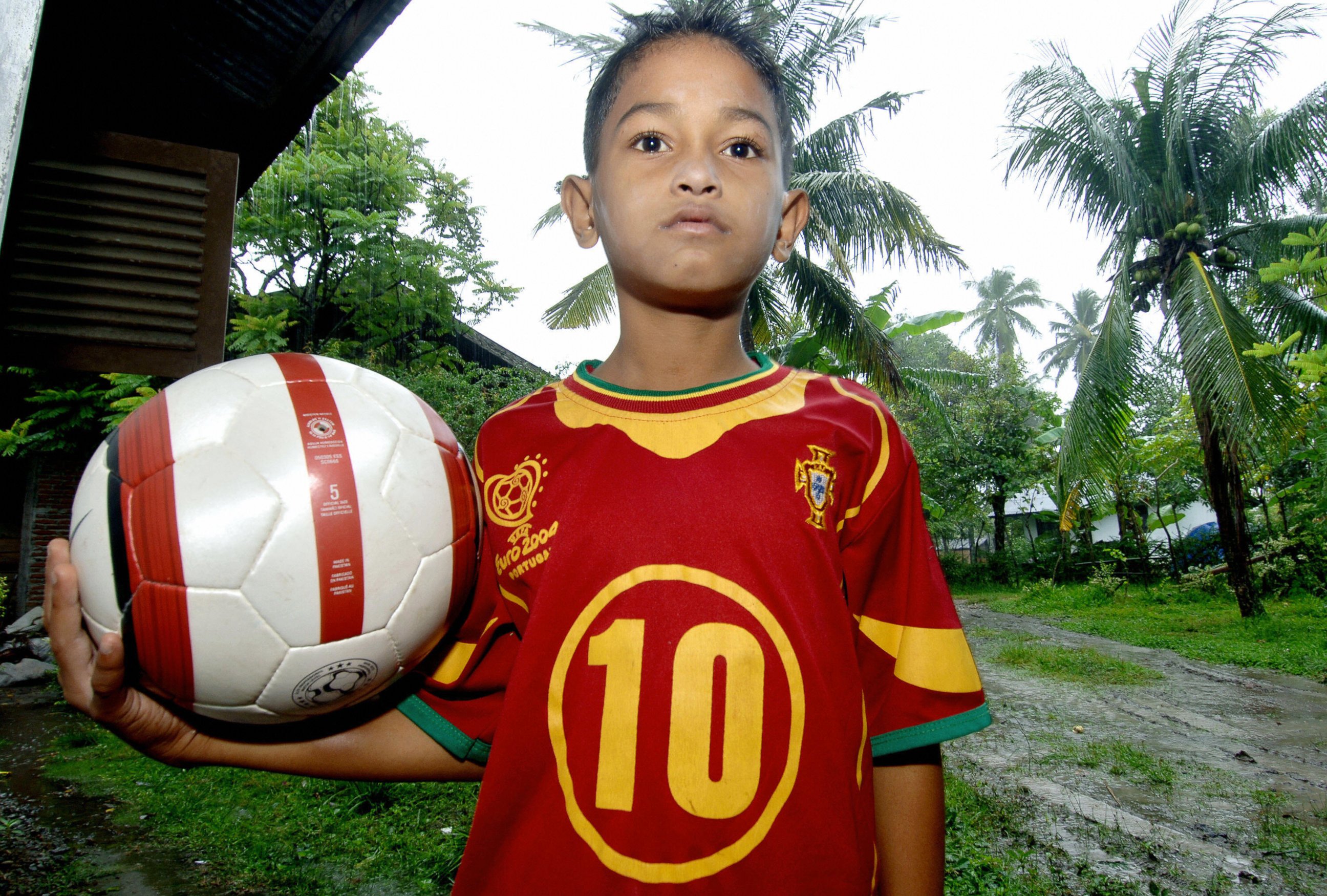 PHOTO: This picture taken by Nov. 30, 2005 shows seven-year old Martunis waiting for rain to stop as he poses with his football at his grandmother's house in Banda Aceh.