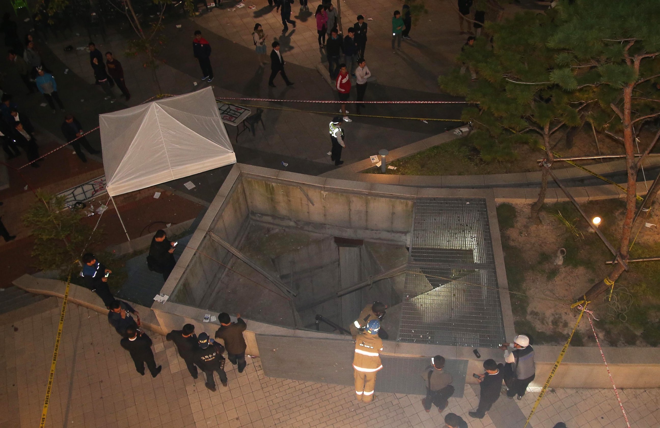 PHOTO: Rescue workers stand around a collapsed ventilation grate on Oct. 17, 2014 in Seongnam, South Korea.