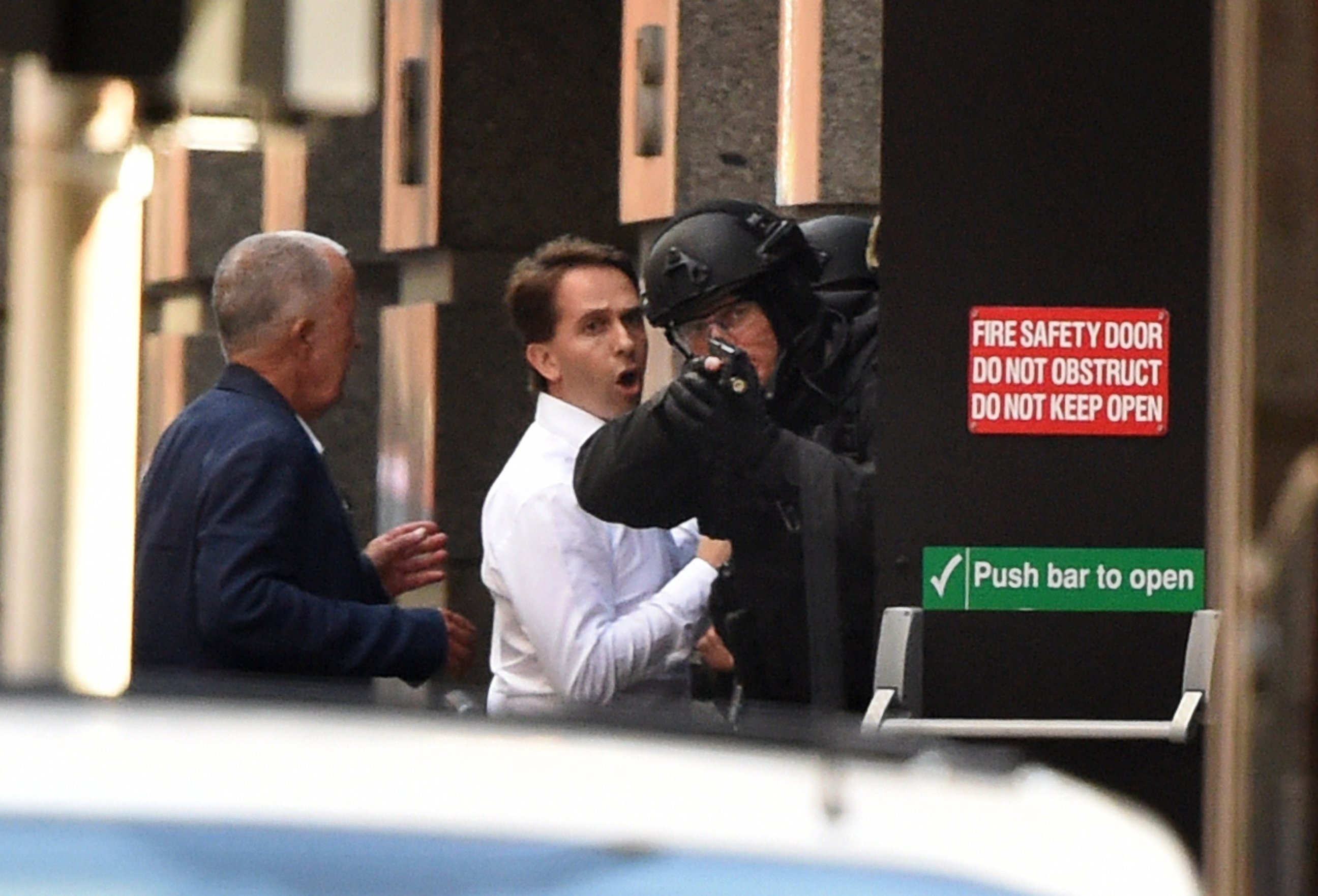 PHOTO: Two hostages, left, run for cover behind a policeman, right, during a hostage siege in the central business district of Sydney on Dec. 15, 2014.  