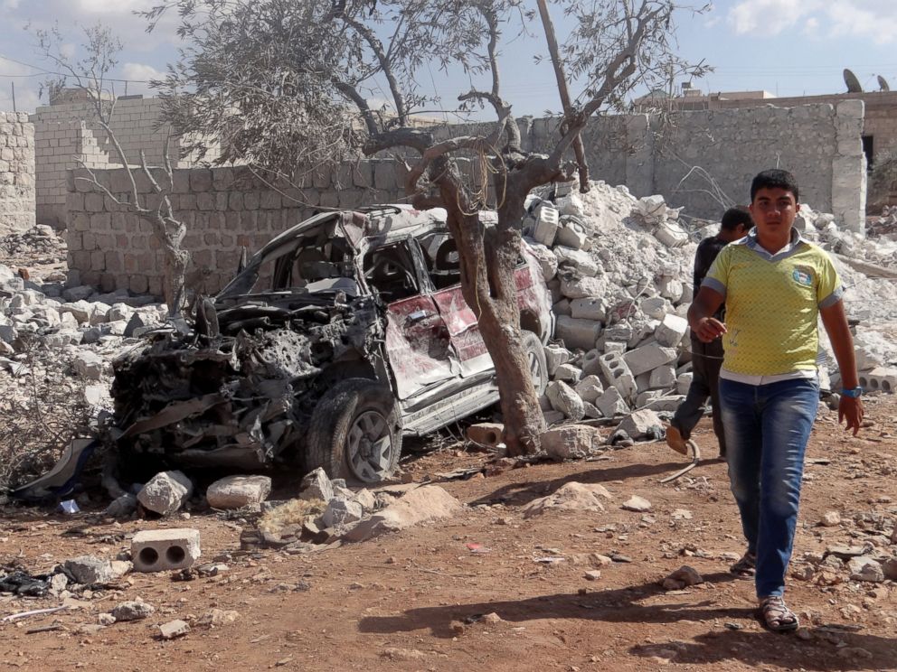 PHOTO: A Syrian youth walks past the wreckage of a vehicle following the U.S.-led coalition airstrikes against ISIS in a residential area in Idlib, Syria on Sept. 23, 2014.