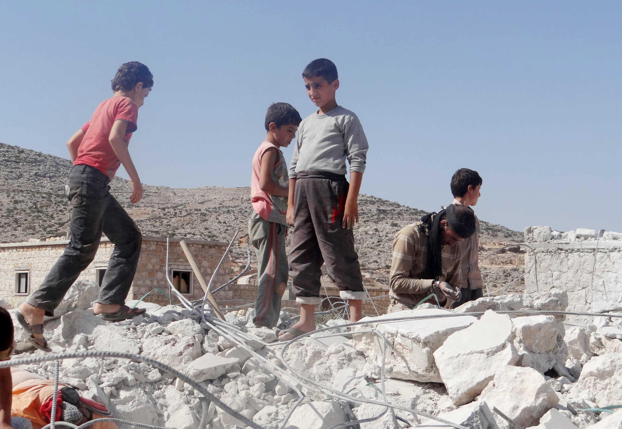 PHOTO: Syrian children collect items from the rubble of a destroyed house following the U.S.-led coalition's airstrikes in Idlib, Syria on Sept. 23, 2014.