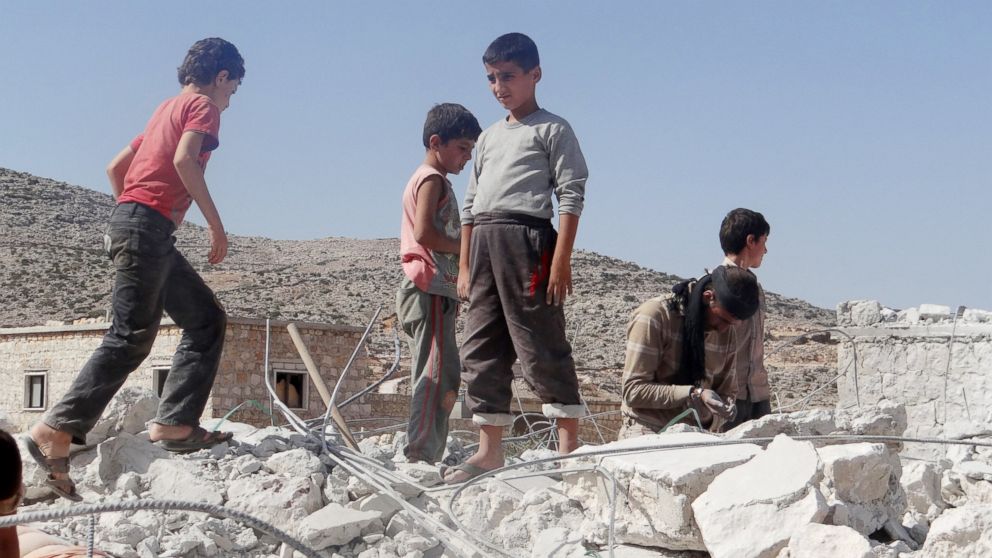 PHOTO: Syrian children collect items from the rubble of a destroyed house following the U.S.-led coalition's airstrikes in Idlib, Syria on Sept. 23, 2014.
