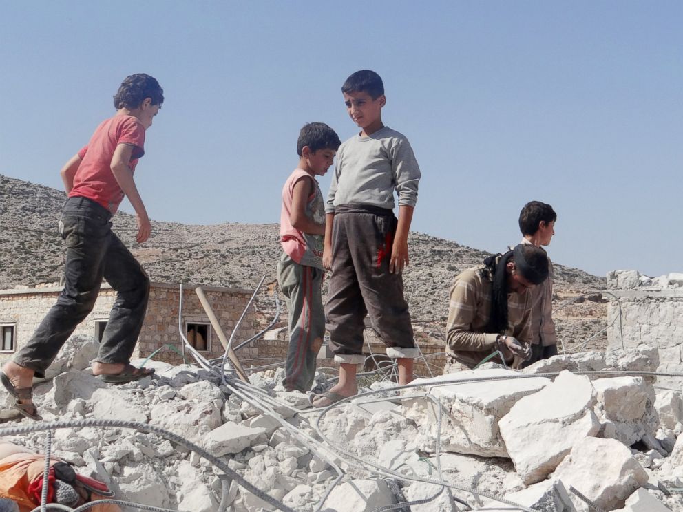 PHOTO: Syrian children collect items from the rubble of a destroyed house following the U.S.-led coalitions airstrikes in Idlib, Syria on Sept. 23, 2014.