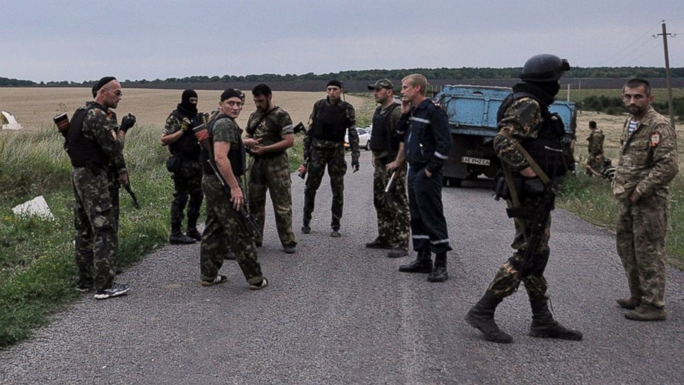 PHOTO: Men wearing military fatigues stand on a road at the site of the wreckage of a Malaysian airliner in rebel-held east Ukraine on July 17, 2014.