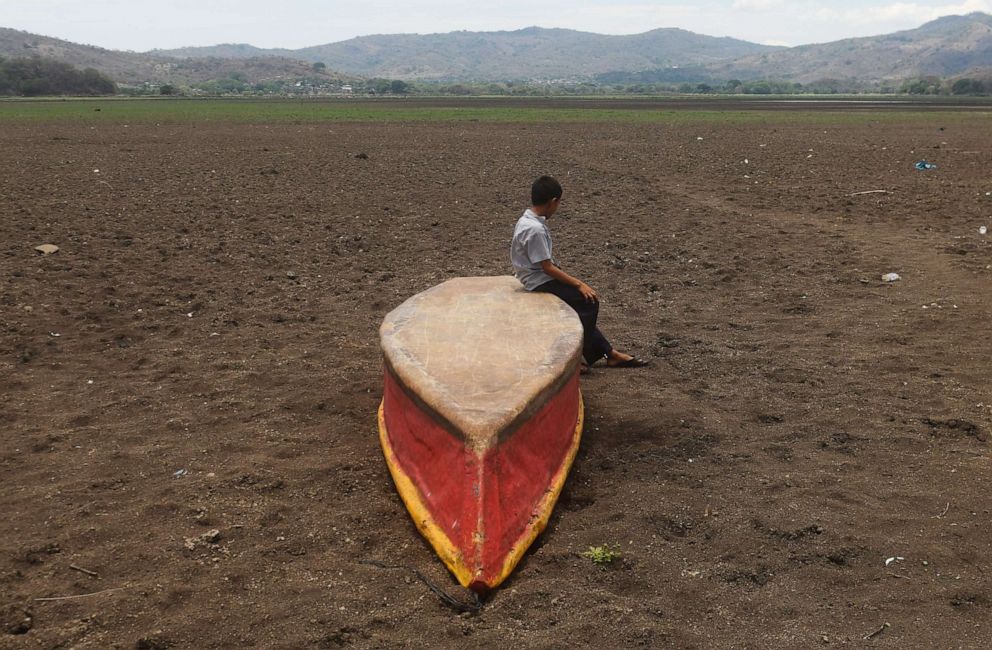 PHOTO: A boy sits on an abandoned boat on what is left of Lake Atescatempa, which has dried up due to drought and high temperatures, in Atescatempa, Guatemala, on May 5, 2017. 