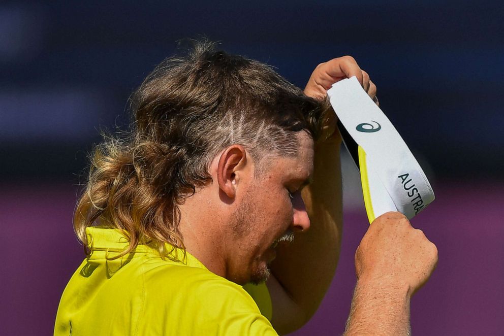 PHOTO: Australia's Cameron Smith, with the letters AUS shaved into his hair, puts on his hat during round 4 of the mens golf individual stroke play during the Tokyo 2020 Olympic Games at the Kasumigaseki Country Club in Kawagoe on Aug. 1, 2021.