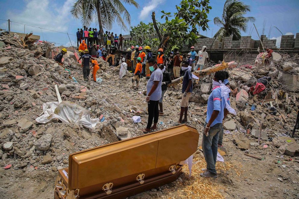 PHOTO: People stand next to the coffin that contains the remains of Francois Elmay whose body was recovered from the rubble of a home destroyed by a 7.2-magnitude earthquake, in Les Cayes, Haiti, Aug. 18, 2021.