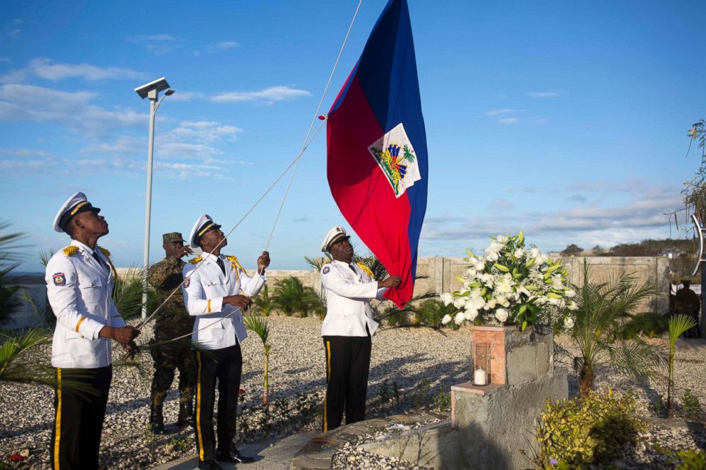 PHOTO: National police officers raise a Haitian national flag during a memorial service honoring the victims of the 2010 earthquake, at Titanyen, a mass burial site north of Port-au-Prince, Haiti, Jan. 12, 2018. 