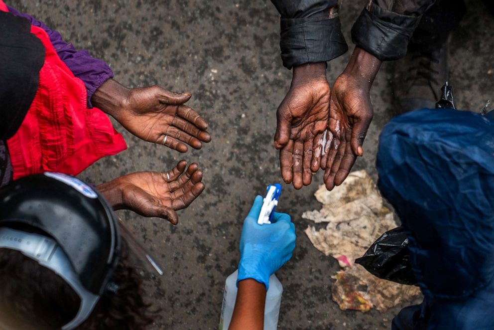 PHOTO: Homeless people waiting to receive food baskets from private donors get their hands sanitized in downtown Johannesburg, South Africa, on April 13, 2020.