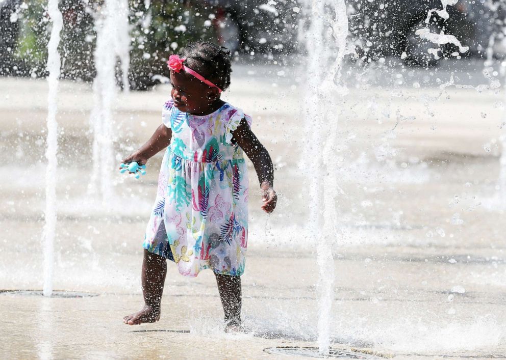 PHOTO: A girl cools off in the water fountains at Canal Park, on July 19, 2019, in Washington, D.C.