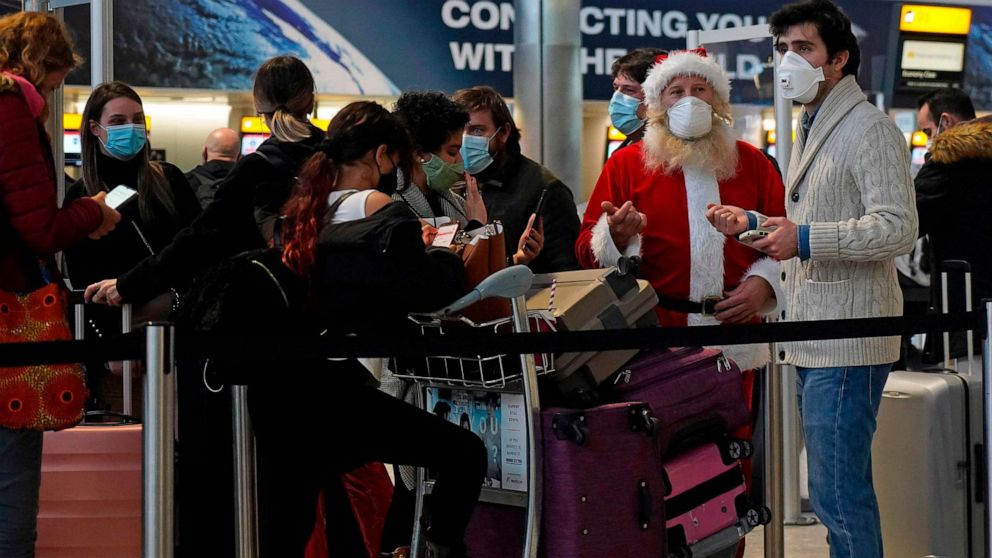 PHOTO: Travelers, one dressed in a Christmas outfit and all wearing face coverings, queue in the departures hall at Heathrow Airport in west London on Dec. 21, 2020, as a string of countries around the world banned travelers arriving from the U.K.