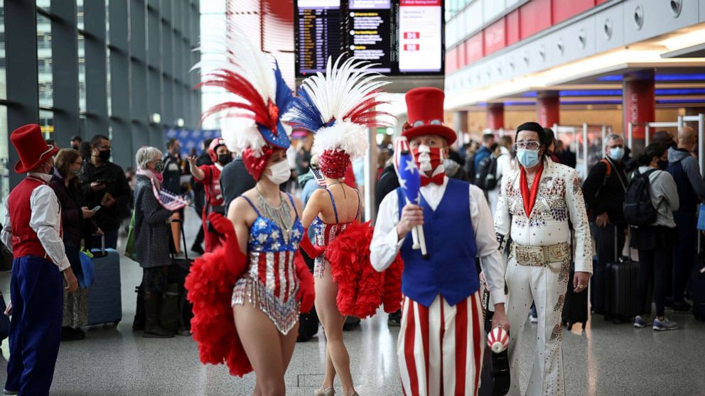 PHOTO: Performers engage with travelers as they queue to check into Virgin Atlantic and Delta Air Lines flights at Heathrow Airport Terminal 3, following the lifting of restrictions on the entry of non-U.S. citizens to the U.S., in London, Nov. 8, 2021.